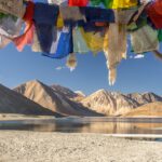 blue yellow and red textile on gray sand near lake and mountain during daytime